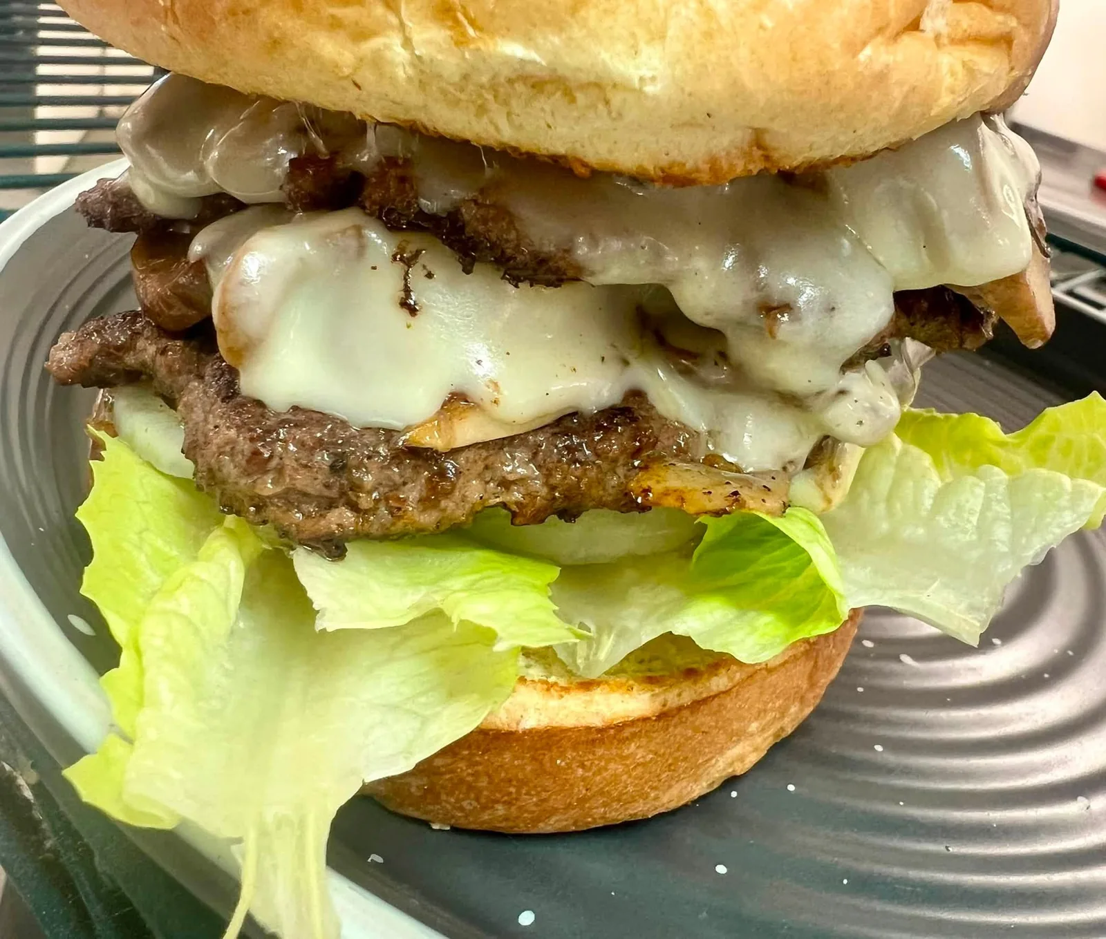 A double cheeseburger with melted cheese, lettuce, and tomato on a toasted bun