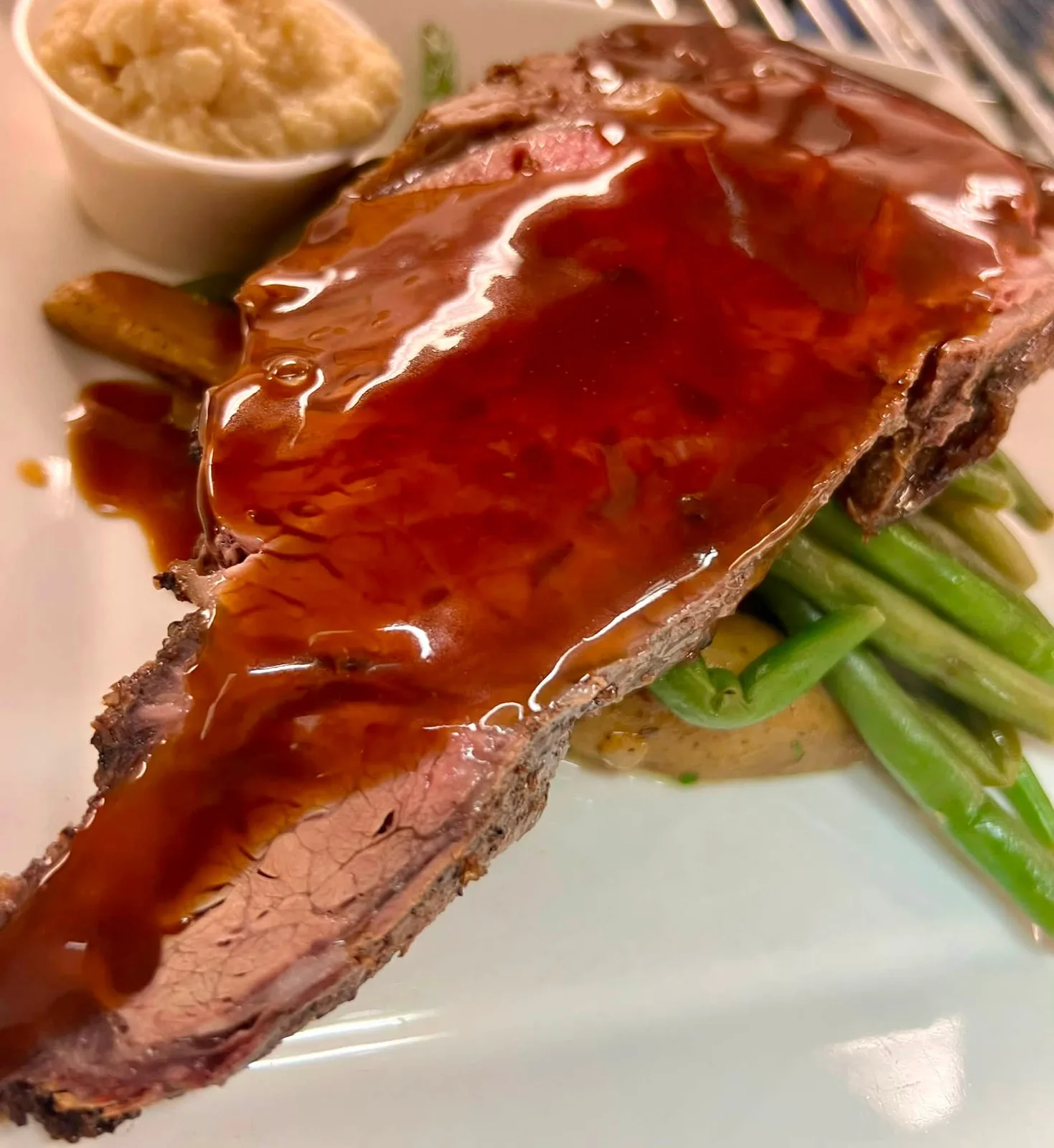 Sliced prime rib finished with pan gravy, whipped potatoes, and green beans
