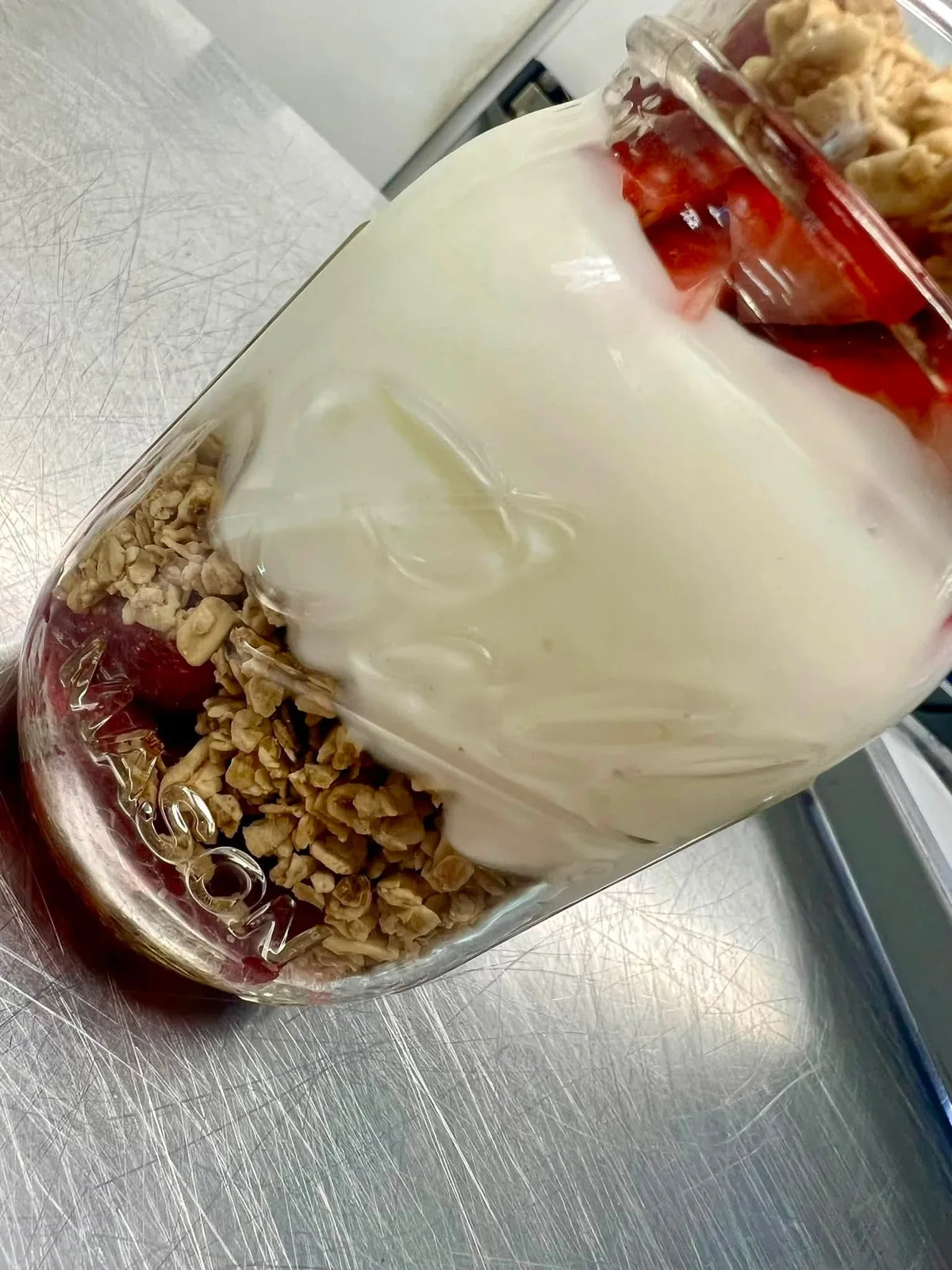 Mason jar parfait layered with house granola, yogurt, and strawberries